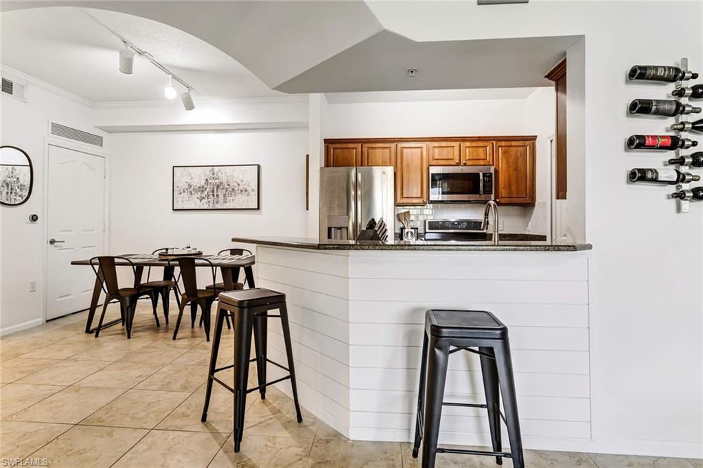 12980 Positano Circle, Unit 202 Naples, FL 34105 - Photo 6 of 27 a living room with stainless steel appliances kitchen island granite countertop furniture and a view of kitchen
