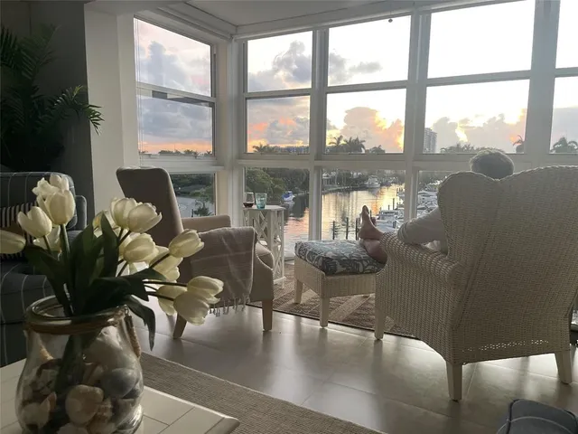 a living room with furniture large window and wooden floor