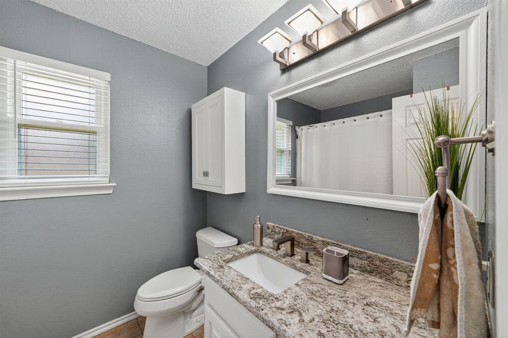 604 McAnear Street Cleburne, TX 76033 - Photo 13 of 18 a bathroom with a granite countertop toilet sink and mirror