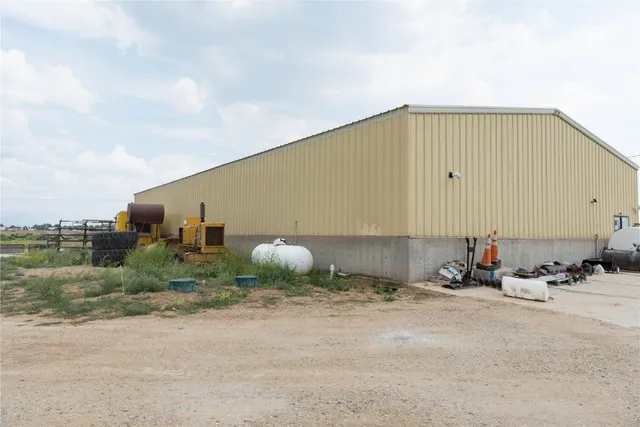 a backyard of a house with table and chairs under an umbrella