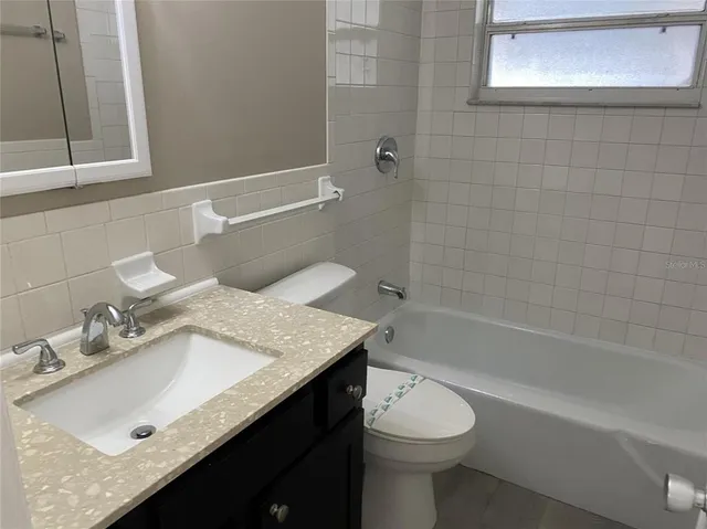 a bathroom with a granite countertop sink a toilet and bathtub