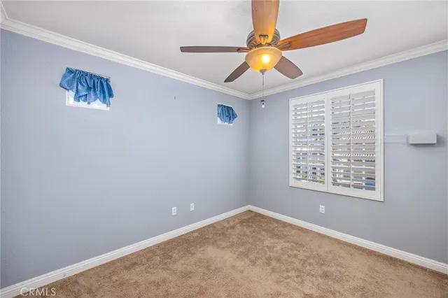 a view of an empty room with window and chandelier fan