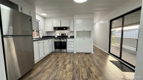 a kitchen with a refrigerator a stove top oven and wooden floor
