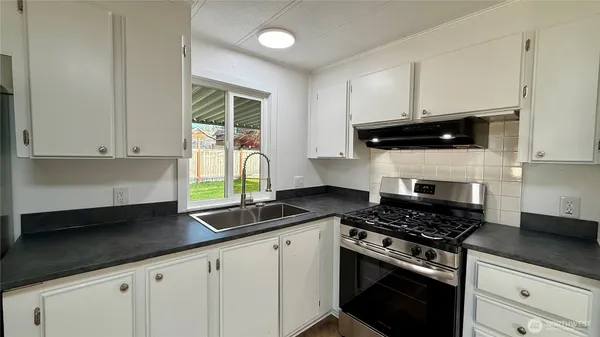 a kitchen with granite countertop white cabinets and black appliances