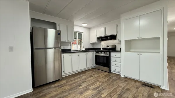 a kitchen with stainless steel appliances granite countertop a refrigerator sink and white cabinets