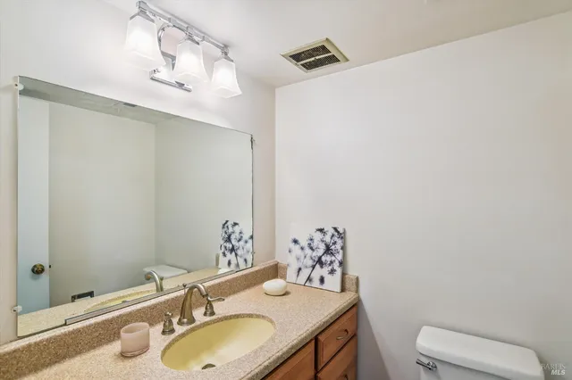 a bathroom with a granite countertop sink a toilet and mirror