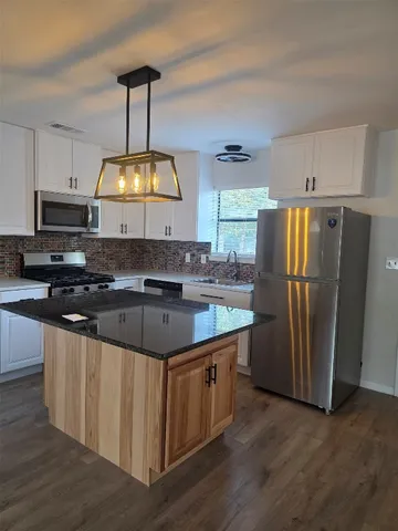 a kitchen with stainless steel appliances granite countertop a refrigerator a stove a sink and a microwave