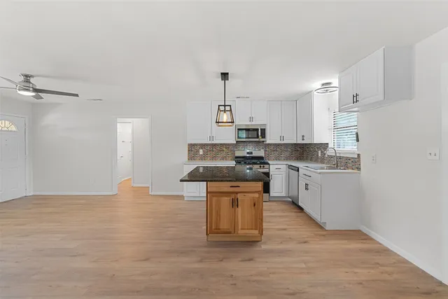 a kitchen with granite countertop a stove top oven a sink dishwasher and a refrigerator with wooden floor