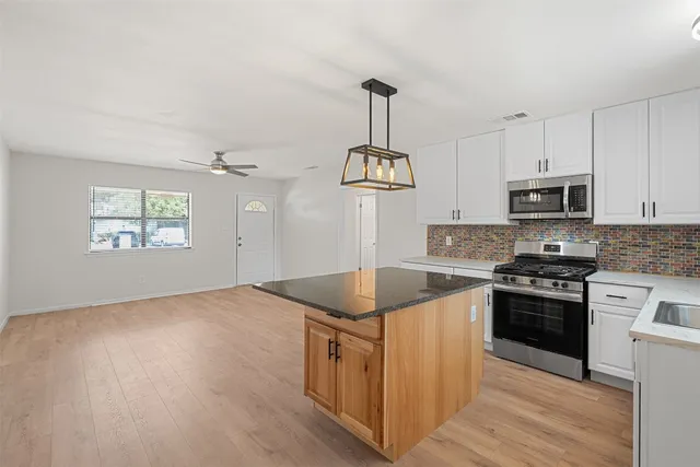 a kitchen with stainless steel appliances granite countertop a stove a sink and a refrigerator