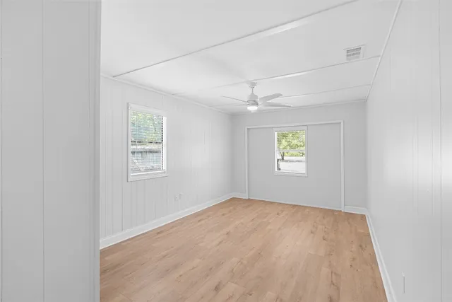an empty room with a window and a ceiling fan