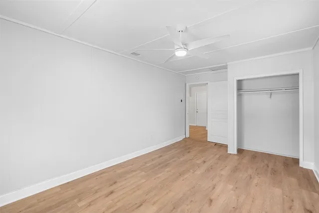 an empty room with wooden floor and fan