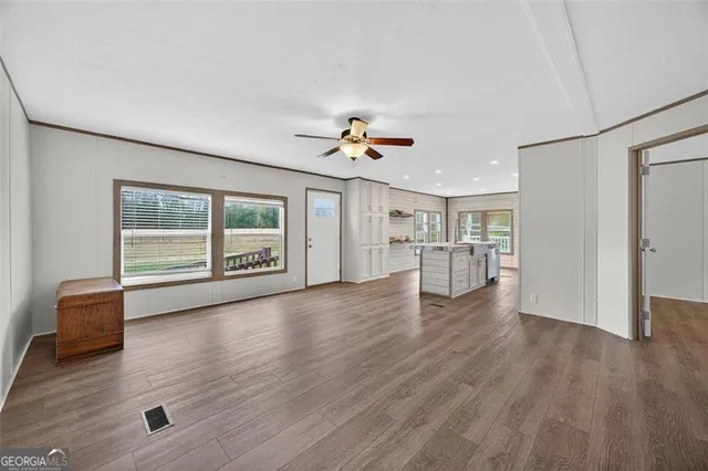 a view of an empty room with a window and wooden floor