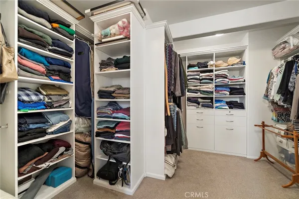 a view of walk in closet with clothes and shoes