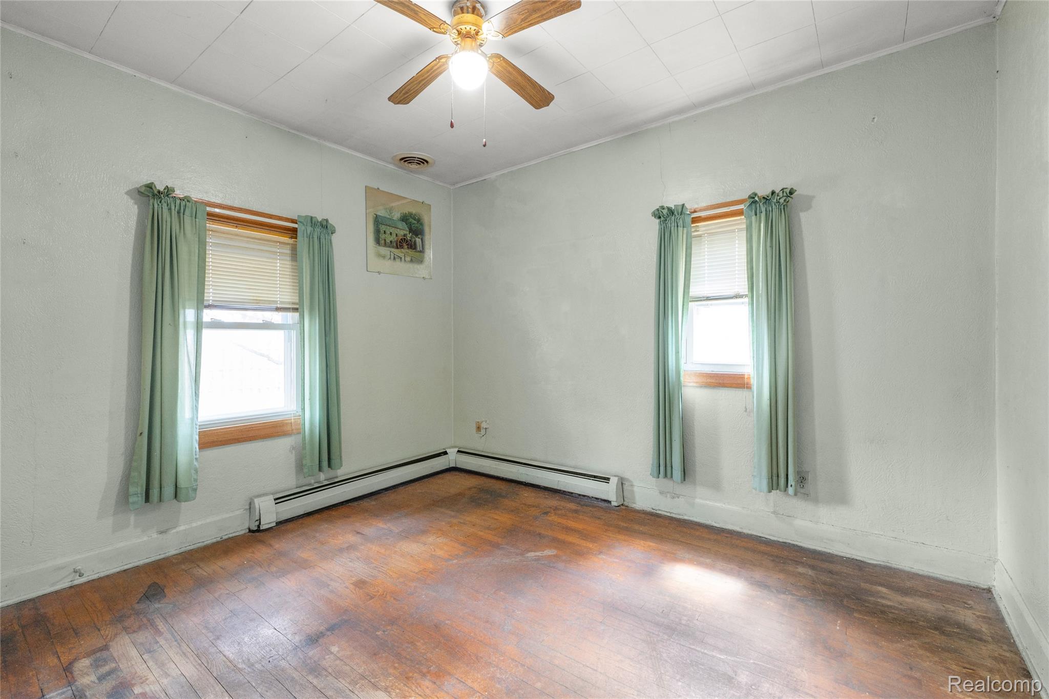 29229 Beverly Road Romulus, MI 48174 - Photo 11 of 17 Unfurnished room with hardwood / wood-style floors, ceiling fan, and a baseboard heating unit
