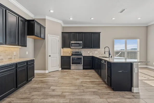 a large kitchen with stainless steel appliances granite countertop a refrigerator and a sink