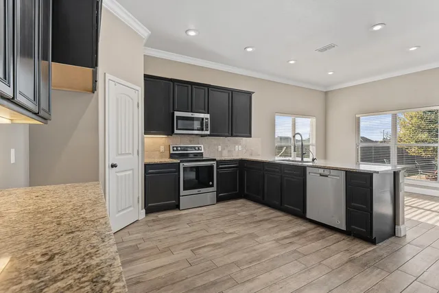 a kitchen with stainless steel appliances kitchen island granite countertop a stove a sink and a refrigerator