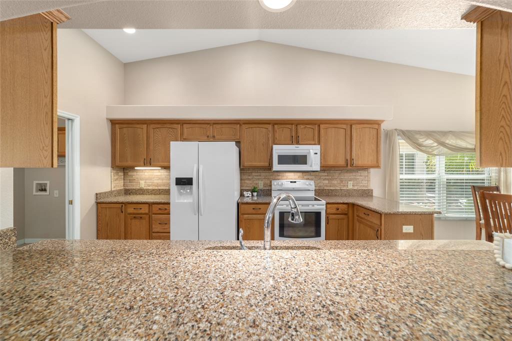 16369 Southwest 14th Avenue Road Ocala, FL 34473 - Photo 14 of 49 a kitchen with stainless steel appliances kitchen island granite countertop a refrigerator and a stove top oven