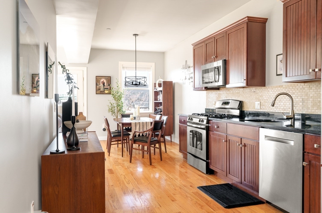 a kitchen with stainless steel appliances granite countertop a refrigerator a stove top oven a sink dishwasher and white cabinets with wooden floor