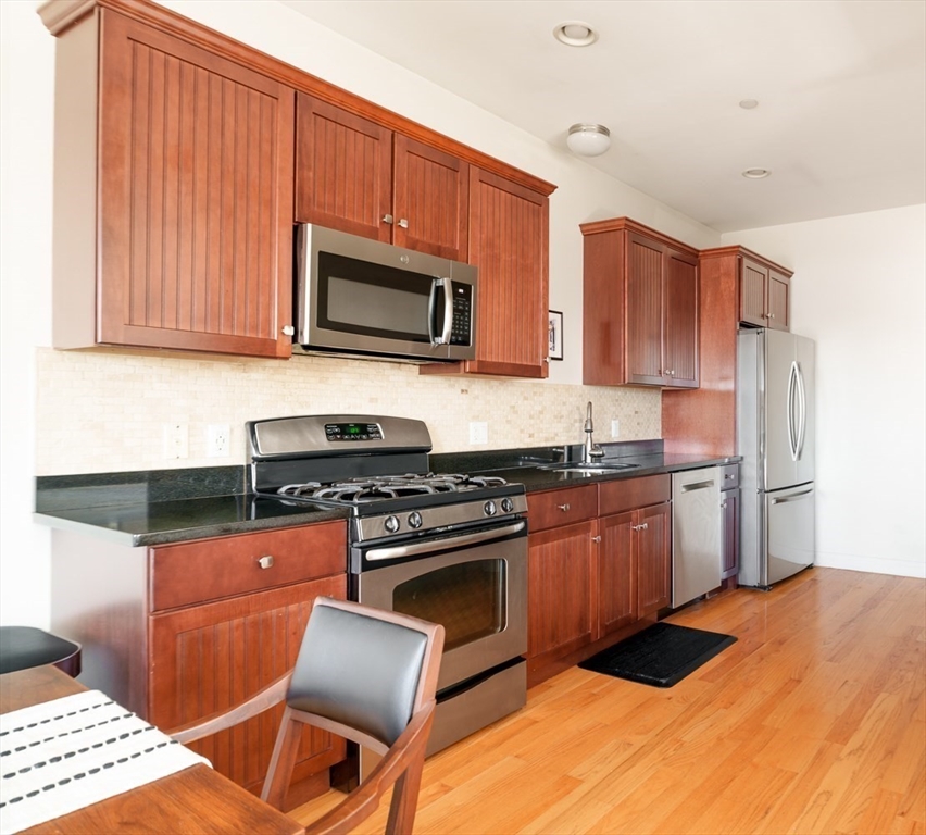 412 Meridian Street, Unit 3 Boston, MA 02128 - Photo 2 of 30 a kitchen with stainless steel appliances granite countertop a stove top oven a sink dishwasher and wooden cabinets