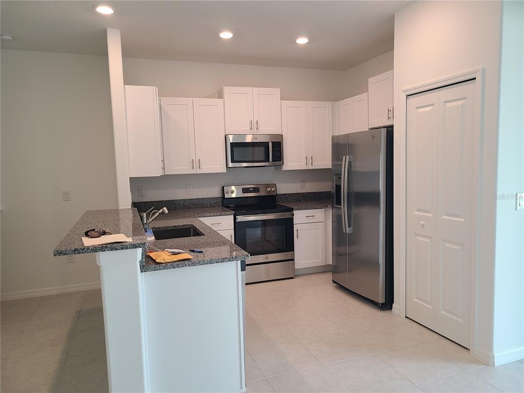 14349 Editors Note Street Ruskin, FL 33573 - Photo 4 of 20 a kitchen with kitchen island a refrigerator and a stove