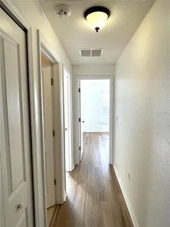 an empty room with wooden floor fan and windows