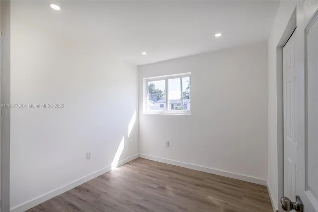 an empty room with wooden floor and entrance