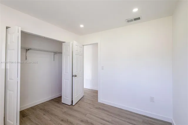 an empty room with a window and wooden floor