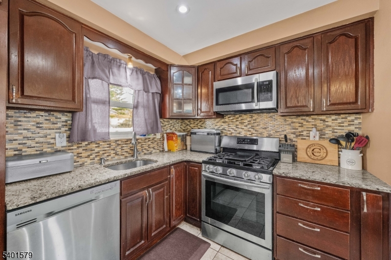 2563 Jackson Avenue Union, NJ 07083 - Photo 15 of 39 a kitchen with granite countertop stainless steel appliances wooden cabinets and a stove top oven