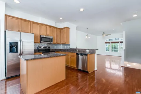 a kitchen with granite countertop wooden floors stainless steel appliances a sink and a window