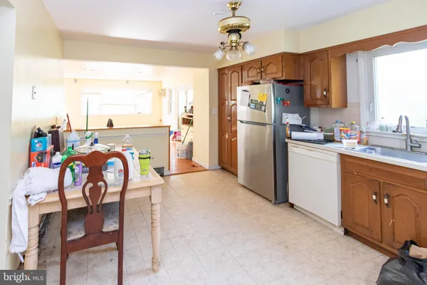 a kitchen with stainless steel appliances granite countertop a dining table chairs refrigerator and sink