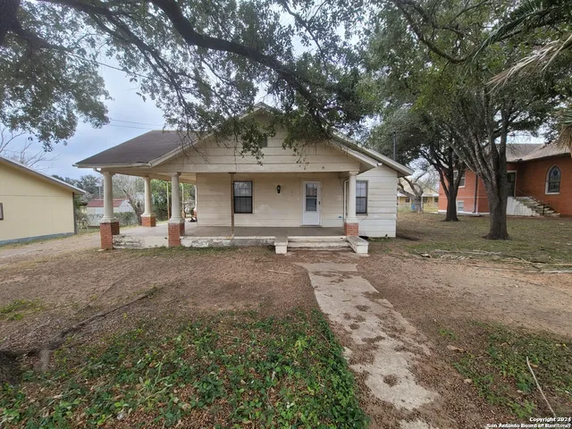 a view of a house with a yard and large tree