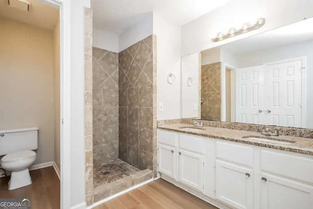 a bathroom with a granite countertop sink toilet and shower