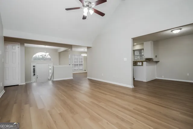 an empty room with wooden floor chandelier and windows