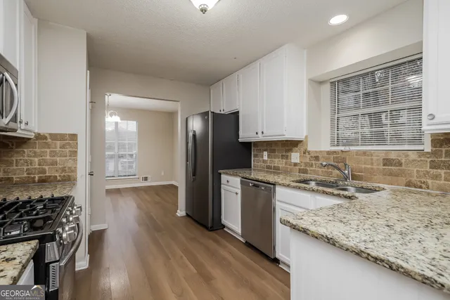 a kitchen with granite countertop a sink stove and refrigerator