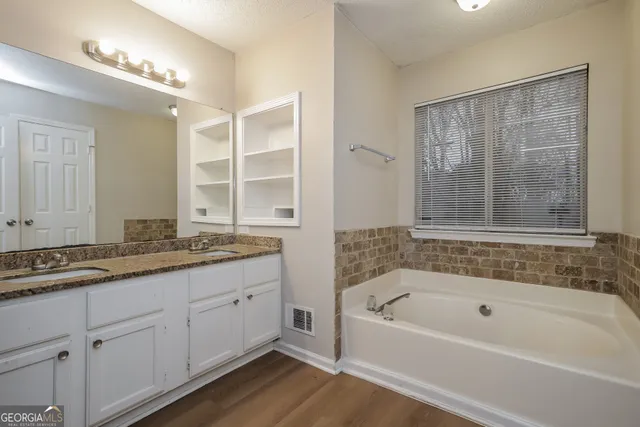 a bathroom with a granite countertop tub a double vanity sink and a large mirror