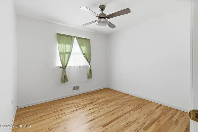 an empty room with a window and a ceiling fan