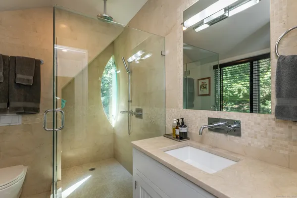 a bathroom with a sink a toilet a mirror and shower