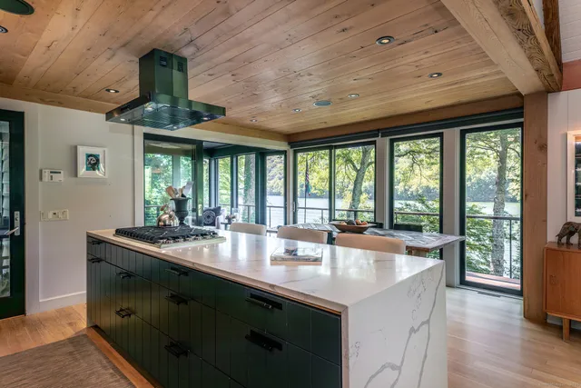 a dining hall with stainless steel appliances granite countertop a sink a stove and a wooden floors