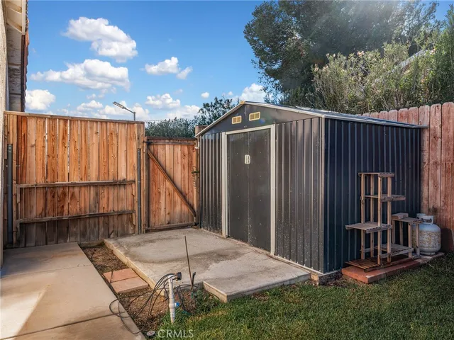a view of a backyard with large trees and wooden fence