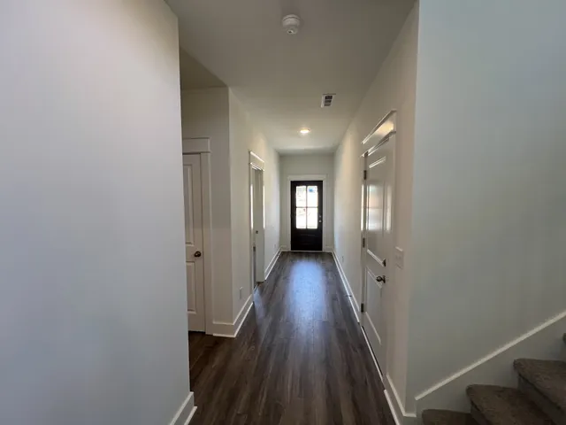 a view of a hallway with wooden floor and staircase