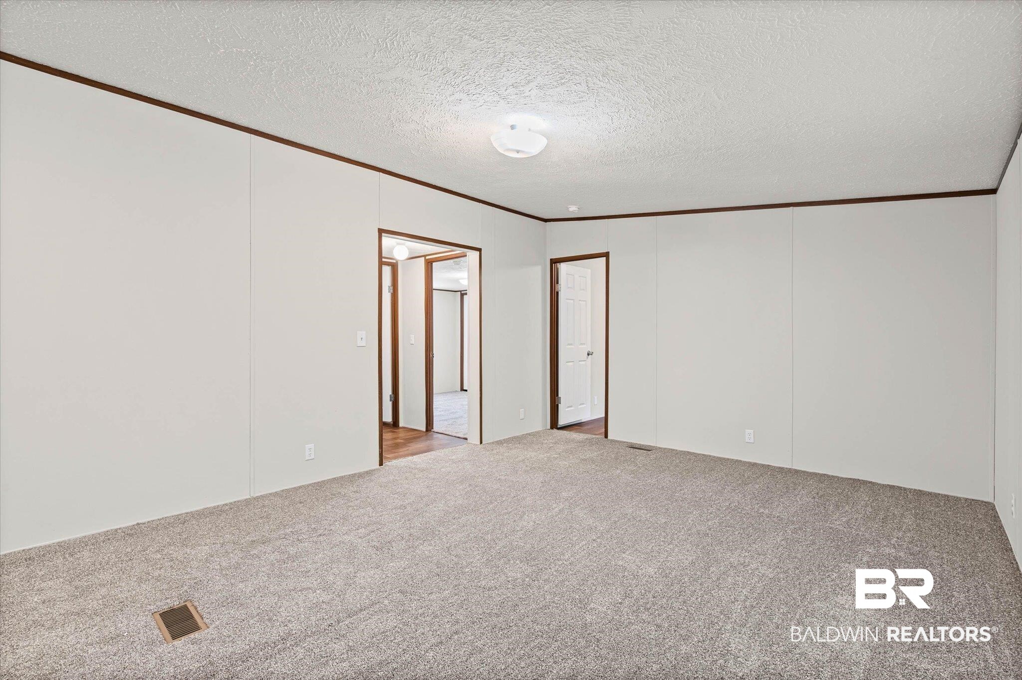25366 Pollard Road Daphne, AL 36526 - Photo 5 of 22 Open room featuring light gray carpeting and white panel walls with dark wood-finish trim