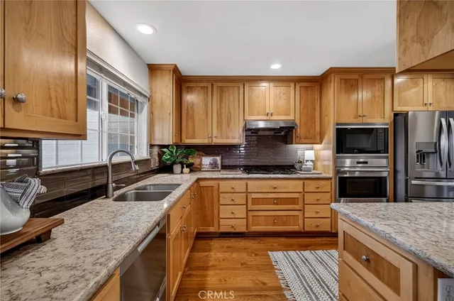 a kitchen with granite countertop wooden cabinets a sink and dishwasher with wooden floor