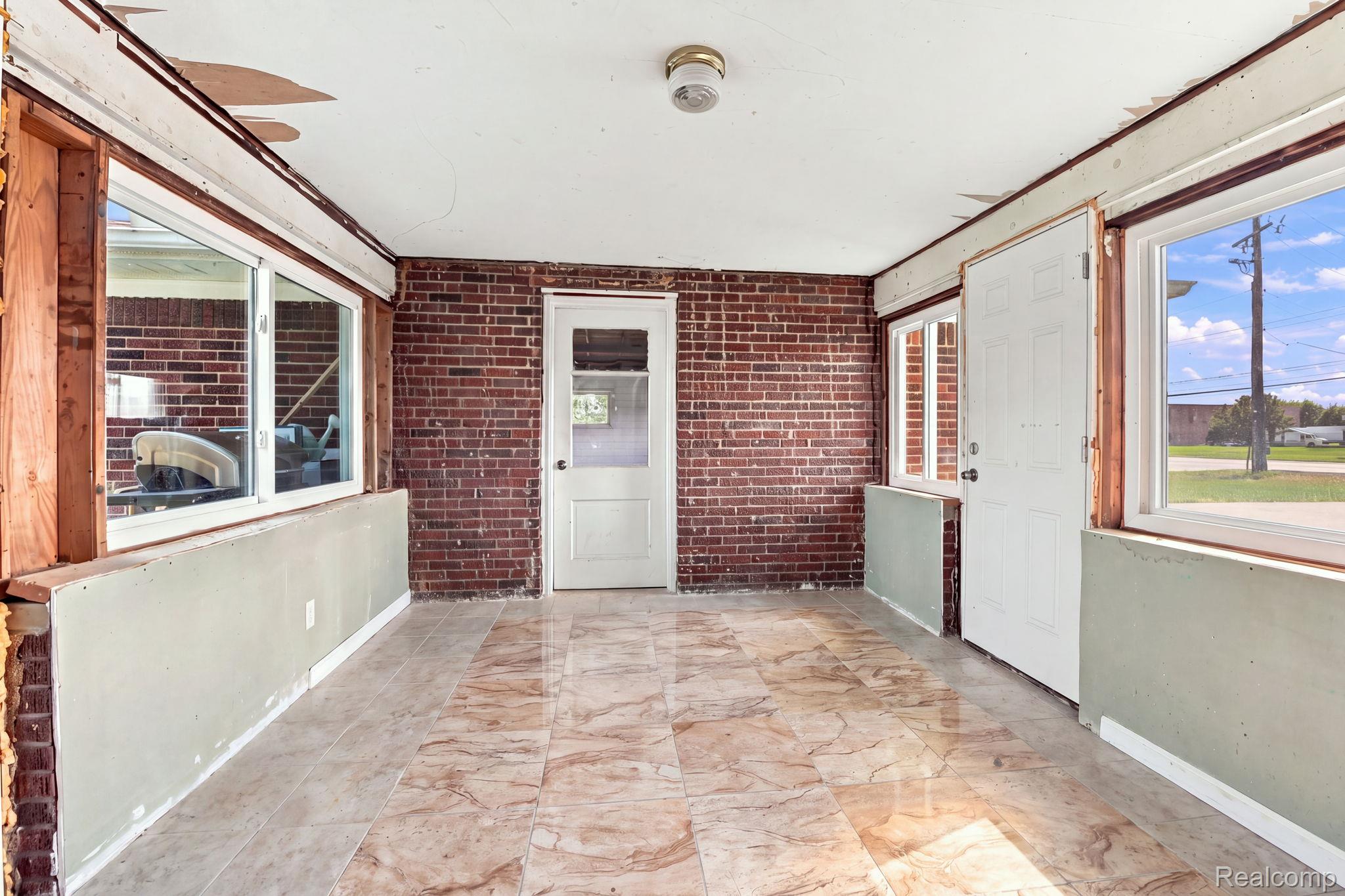 5353 18 Mile Road Sterling Heights, MI 48314 - Photo 37 of 53 Tiled flooring, exposed brick wall, multiple window openings, and a paneled door with a frosted glass insert