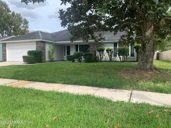 a front view of a house with a yard and trees
