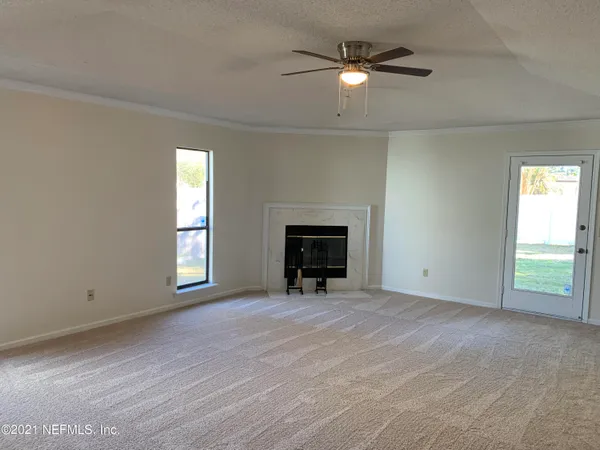 an empty room with chandelier fan and windows