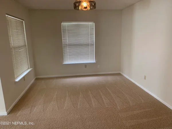 an empty room with windows and chandelier fan