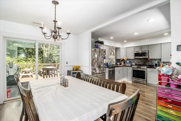 a view of a dining room and livingroom with furniture wooden floor a chandelier