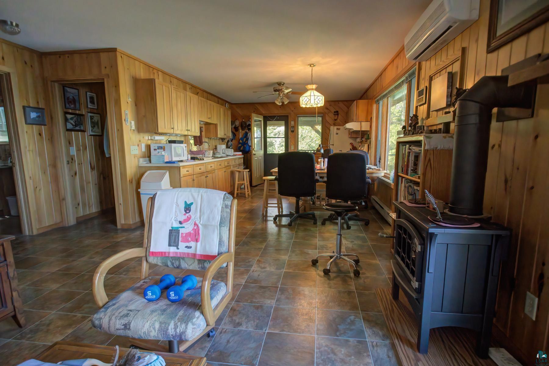 2811 Schaeffer Road Ely, MN 55731 - Photo 21 of 40 Wood-paneled interior with built-in cabinetry, tile flooring, and a free-standing fireplace