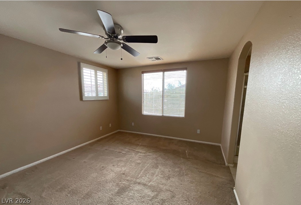 10841 Paradise Road Henderson, NV 89052 - Photo 21 of 35 A comfortable bedroom features plush carpeting, window blinds, and a practical ceiling fan for year-round comfort.