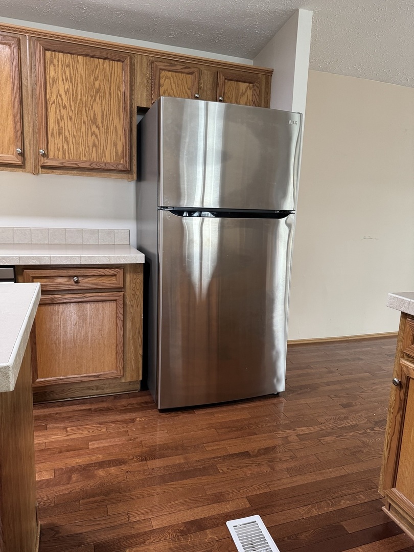 400 James Road Elwood, IL 60421 - Photo 5 of 25 a view of a refrigerator in kitchen and an empty room with wooden floor